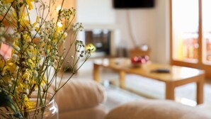 Una sala de estar con un sofá, una mesa de centro y un televisor montado en la pared.