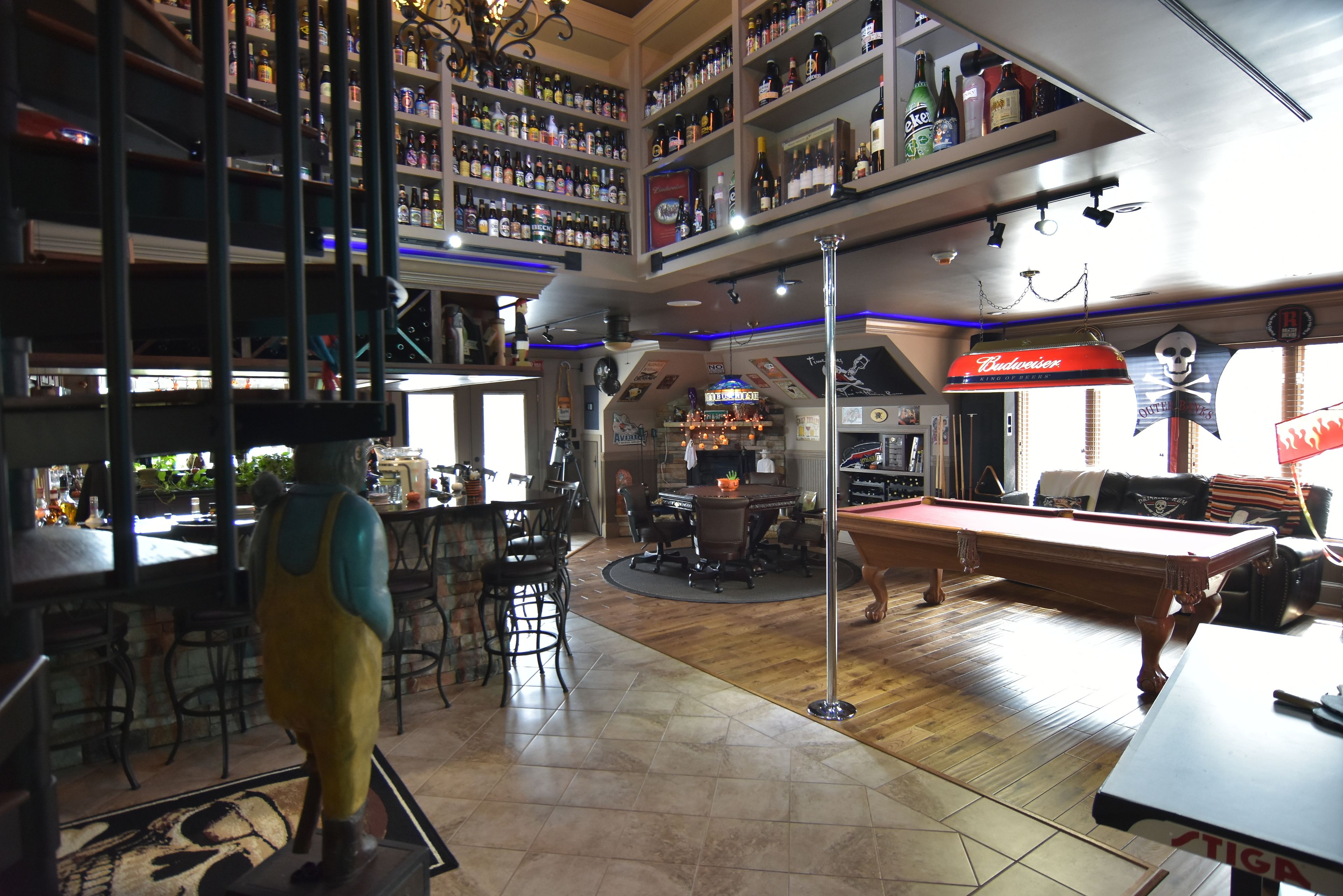 A bar area with a pool table, bar stools, and shelves stocked with liquor.