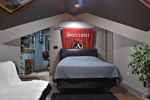 Una camera da letto con un letto, uno striscione rosso con la scritta 'Surrender', una pianta e uno specchio.