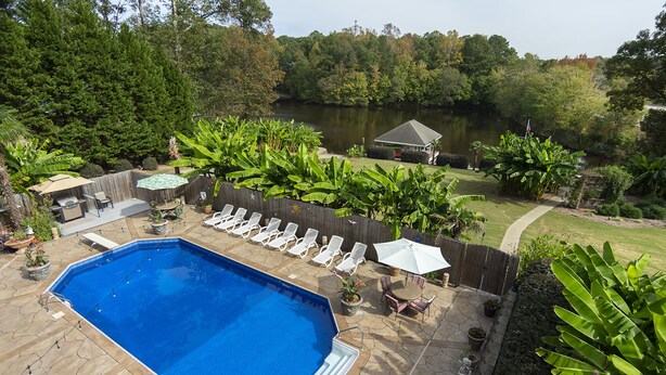A backyard with a swimming pool, lounge chairs, and a barbecue area. - The Lakeside Resort (Zebulon)