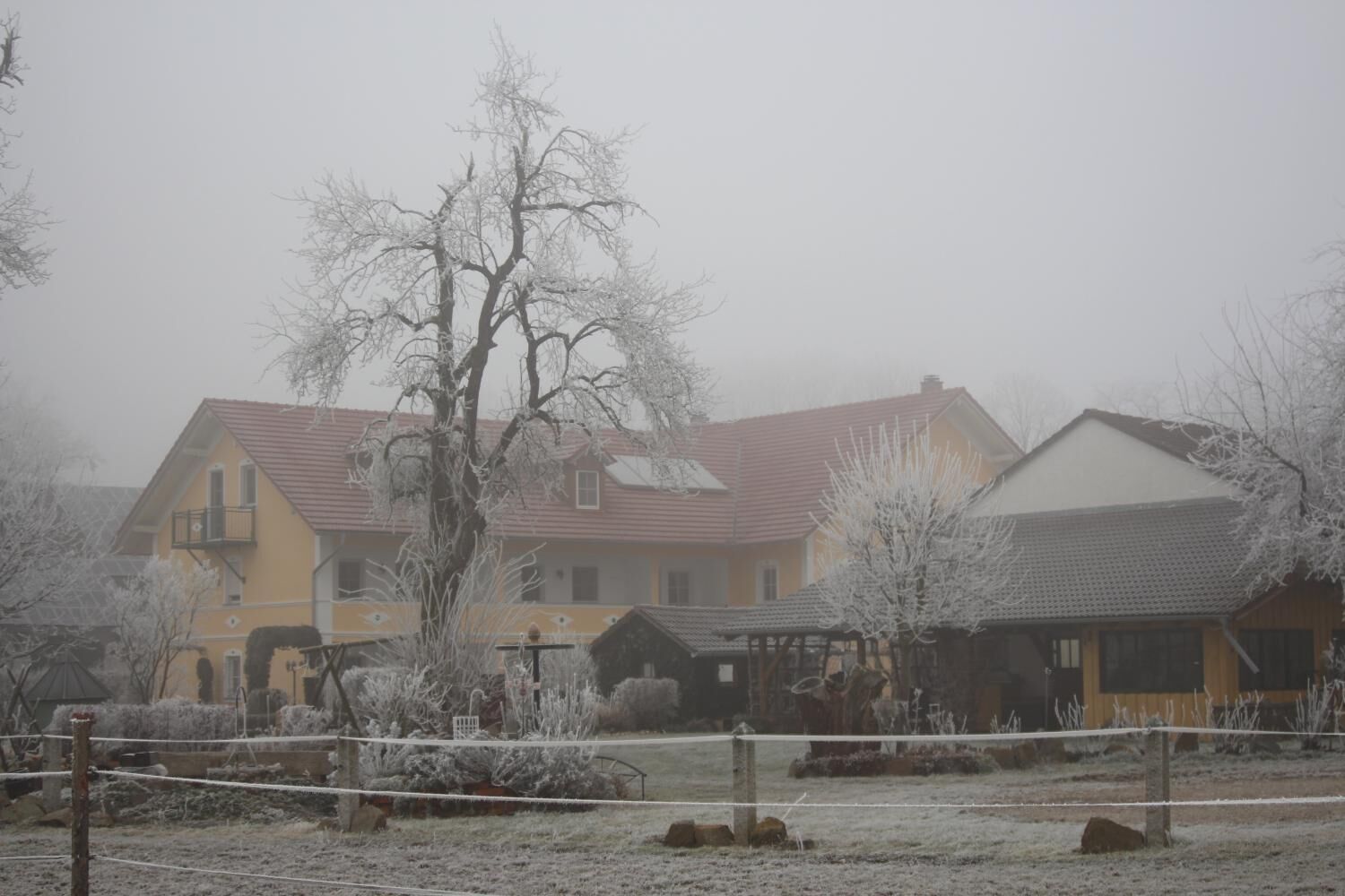 Ett bostadsområde med hus, ett staket och ett snötäckt landskap.