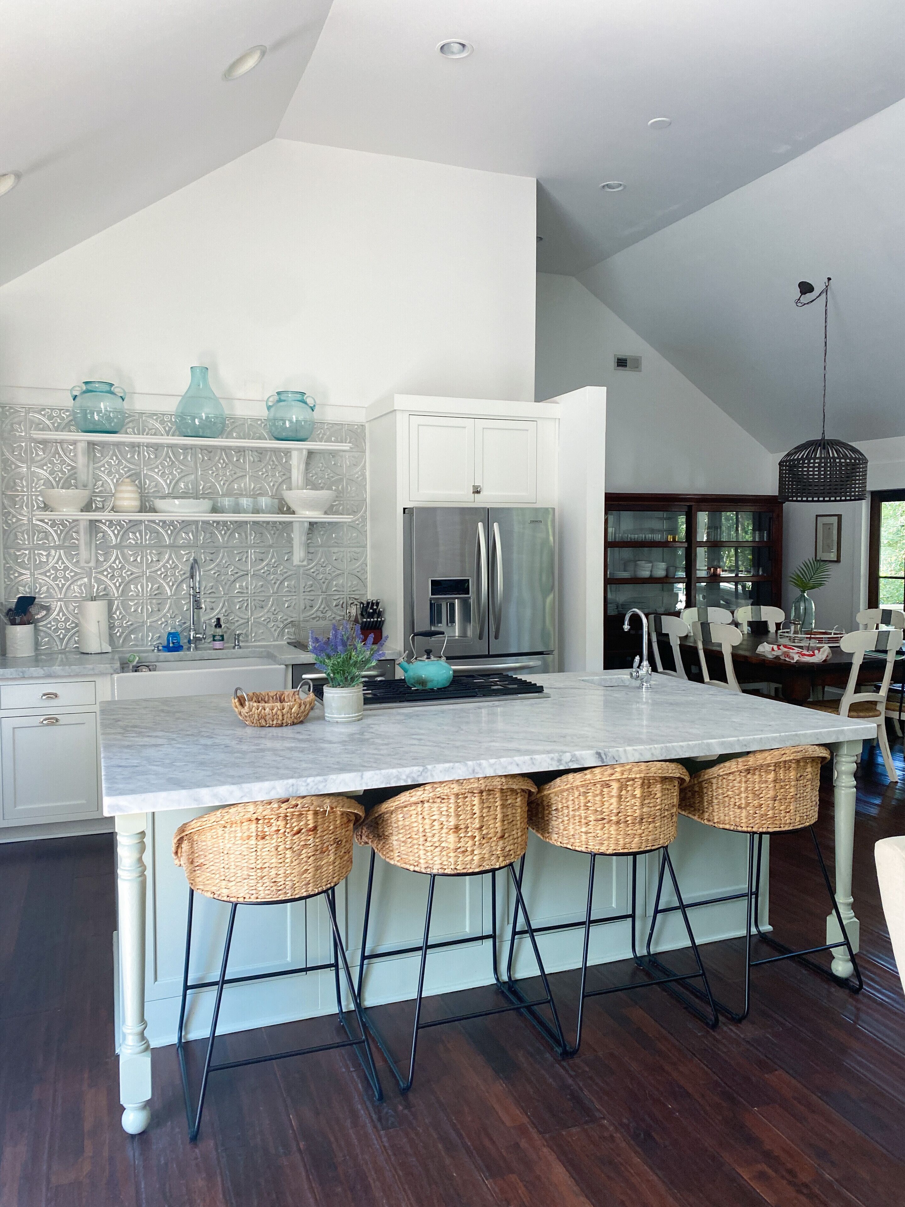A modern kitchen with a central island, white cabinetry, and a dining area with a chandelier.