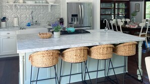 A modern kitchen with a central island, white cabinetry, and a dining area with a chandelier.