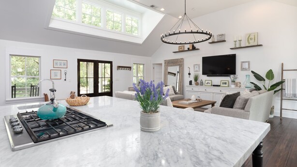 A spacious kitchen with a large island, a modern chandelier, and a large window providing natural light.