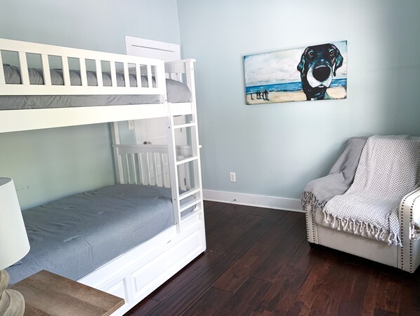 A room with a bunk bed, a couch, and a painting of a dog on the wall.