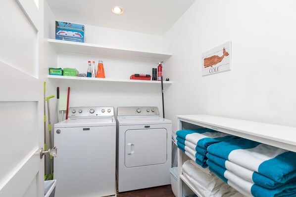 Un lavadero con dos lavadoras Maytag, un estante con útiles de limpieza y un mapa enmarcado en la pared.