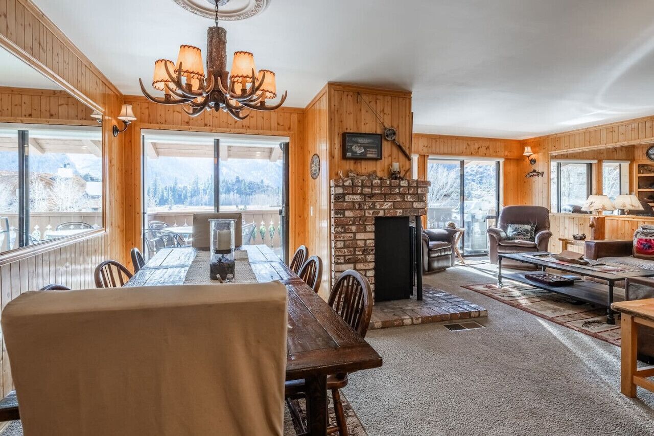 Un chalet confortable doté d’un coin repas, d’une cheminée et de grandes fenêtres offrant une vue sur les montagnes.