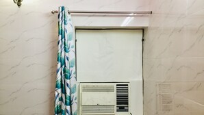A bathroom with a shower curtain, a towel rack, and a wall-mounted air conditioning unit. - 2Bedroom Set Aastha @ GIP Mall Noida (Noida)