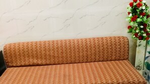 A sofa with a geometric pattern in a room with a marble floor and a floral arrangement. - 2Bedroom Set Aastha @ GIP Mall Noida (Noida)
