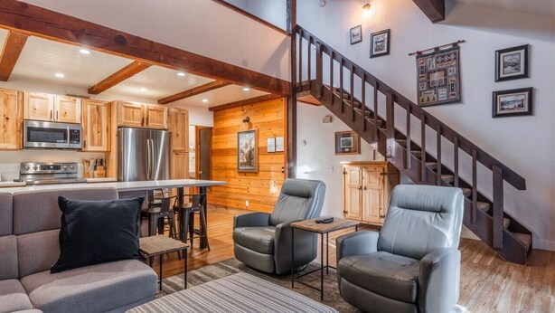 A modern living room with a sofa, two armchairs, a coffee table, and a kitchen in the background. - June Lake Sierra Suns 4 -Spacious (June Lake)