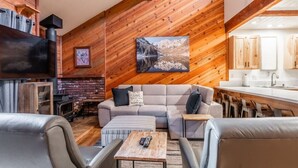 A cozy living room with a fireplace, a sofa, a coffee table, and a TV. - June Lake Sierra Suns 4 -Spacious (June Lake)