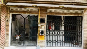Un edifici amb una entrada tancada per reixa, un senyal d'advertència per una conducció de gas a alta pressió i una porta metàl·lica.