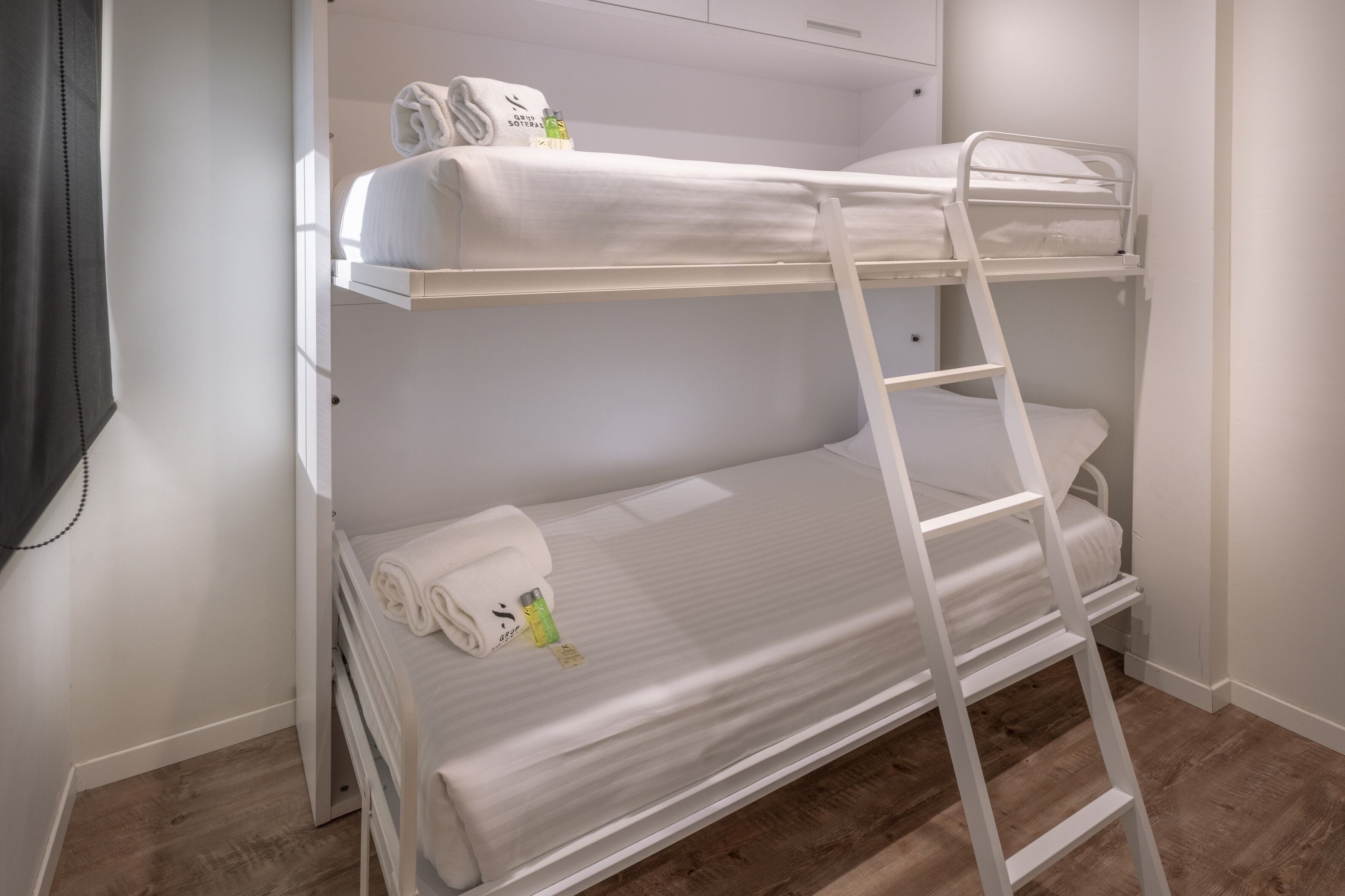 A bunk bed with a ladder, a towel, and toiletries on the top bunk.