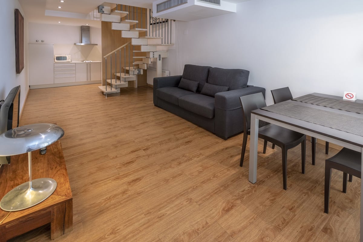 Un espace de vie moderne comprenant un canapé, une table à manger et un escalier.