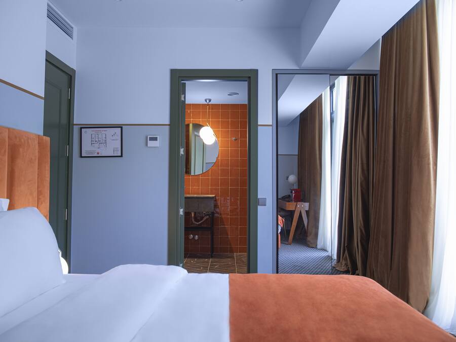 Ein Hotelzimmer mit Bett, Bad und Blick auf den Flur.