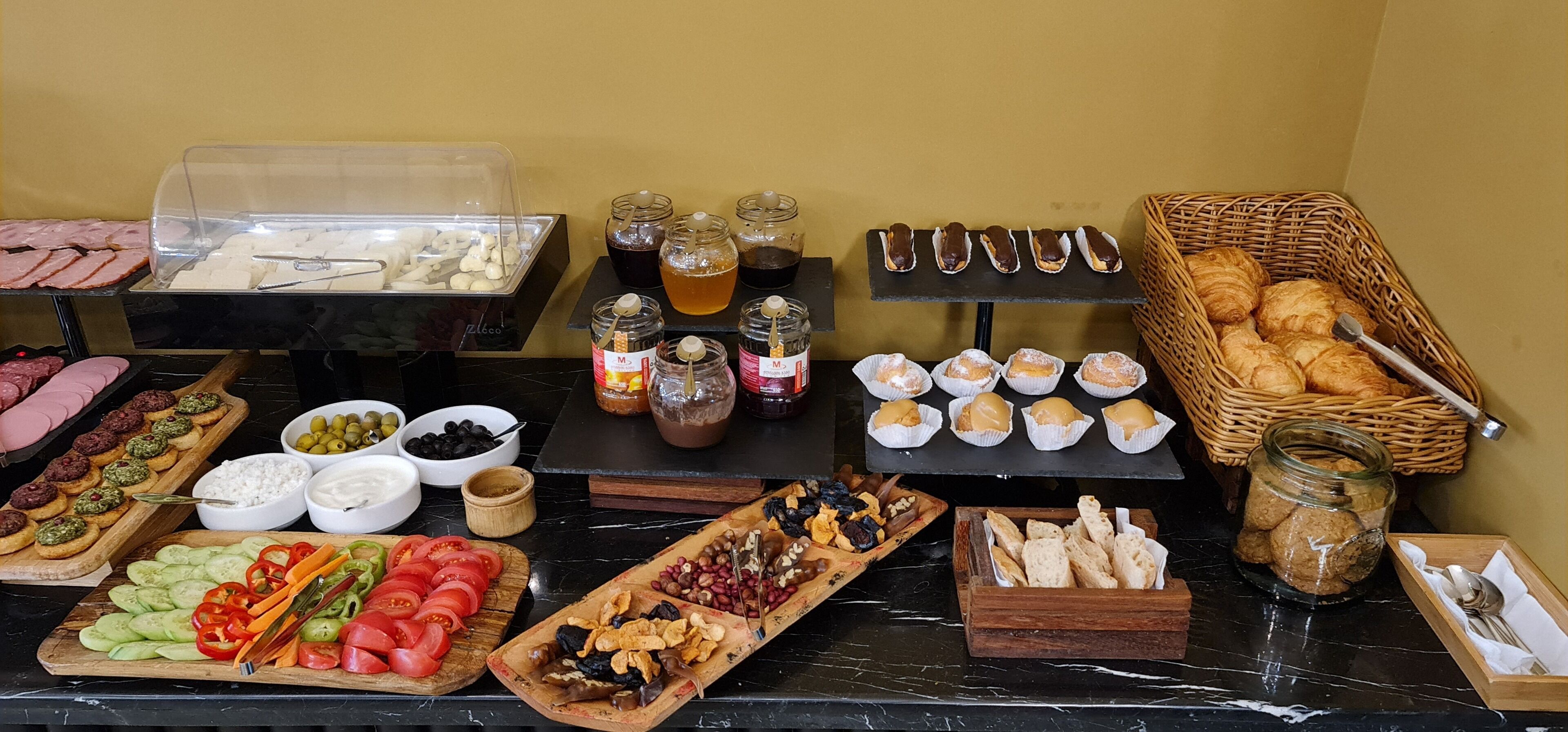 A buffet with various food items including meats, cheeses, fruits, and pastries.