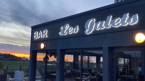 A bar named "Les Galets" with outdoor seating and a view of the sunset. - Hôtel Les Galets (Criel-sur-Mer)
