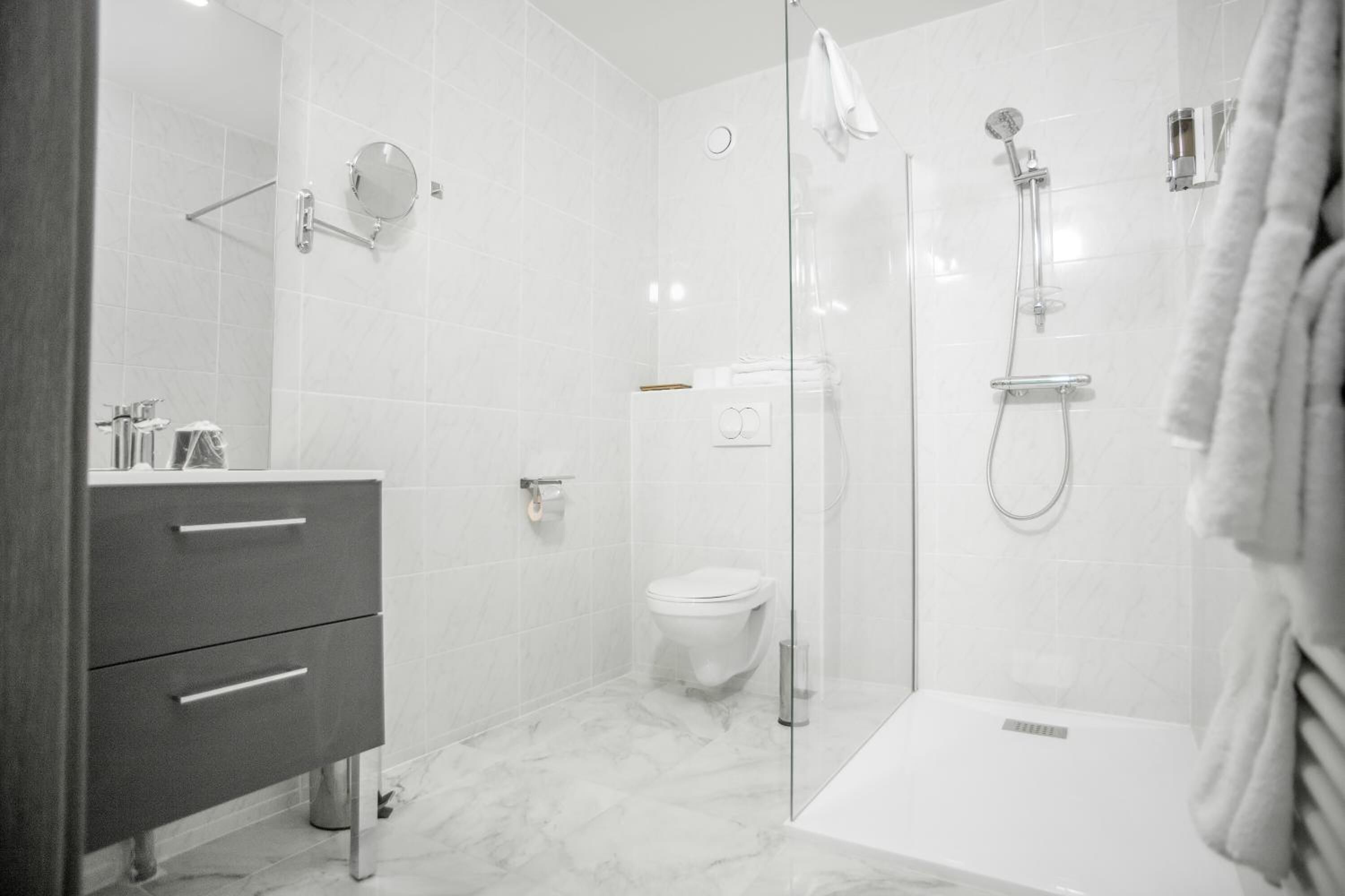 A modern bathroom with a glass-enclosed shower, a toilet, and a vanity with drawers.