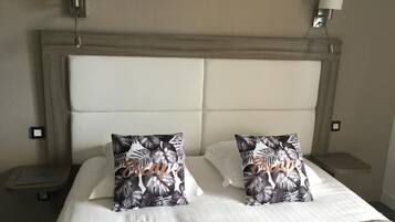A hotel room with a large bed, two nightstands, and wall-mounted lamps.