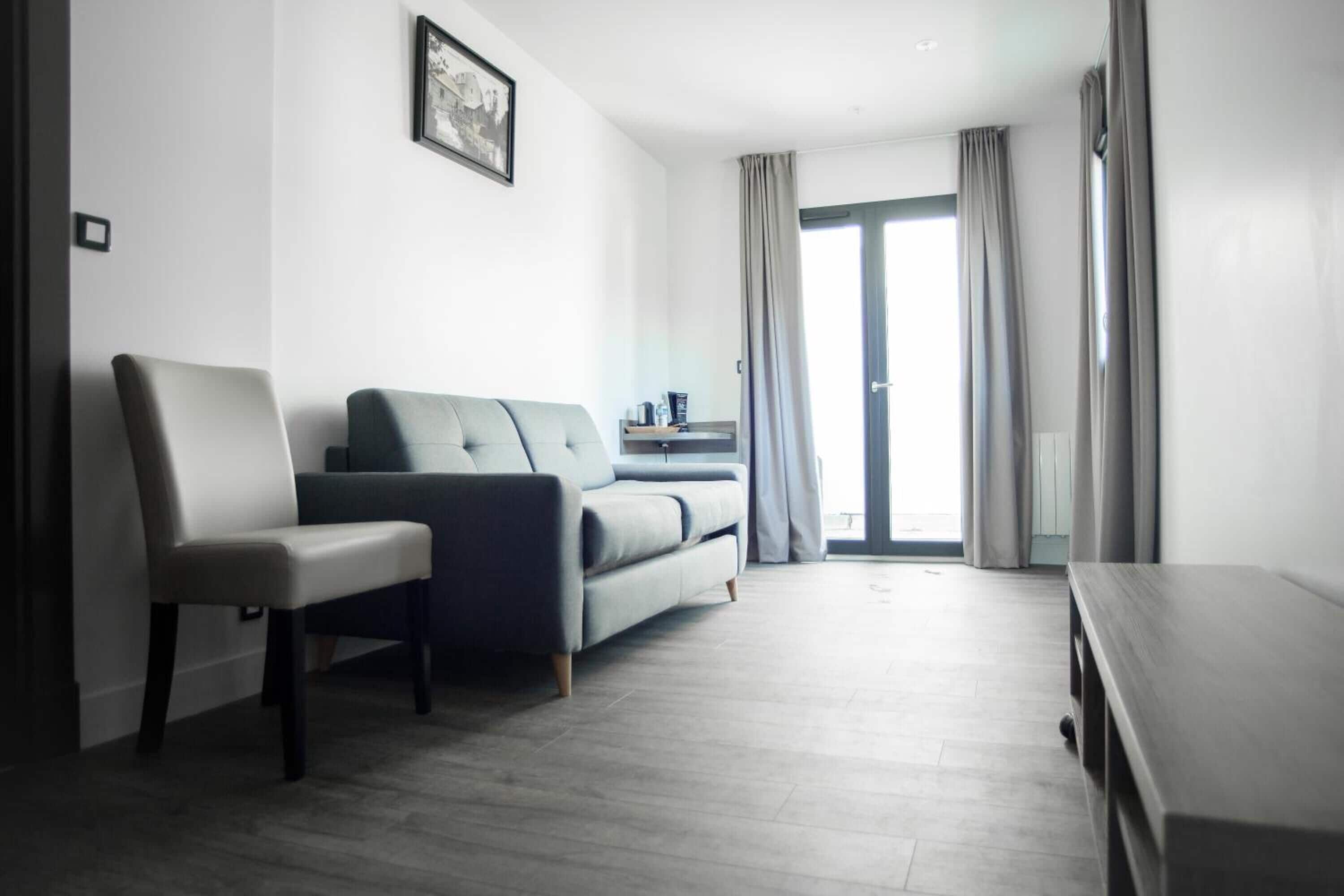 A modern living room with a grey sofa, a white armchair, and a wooden coffee table.