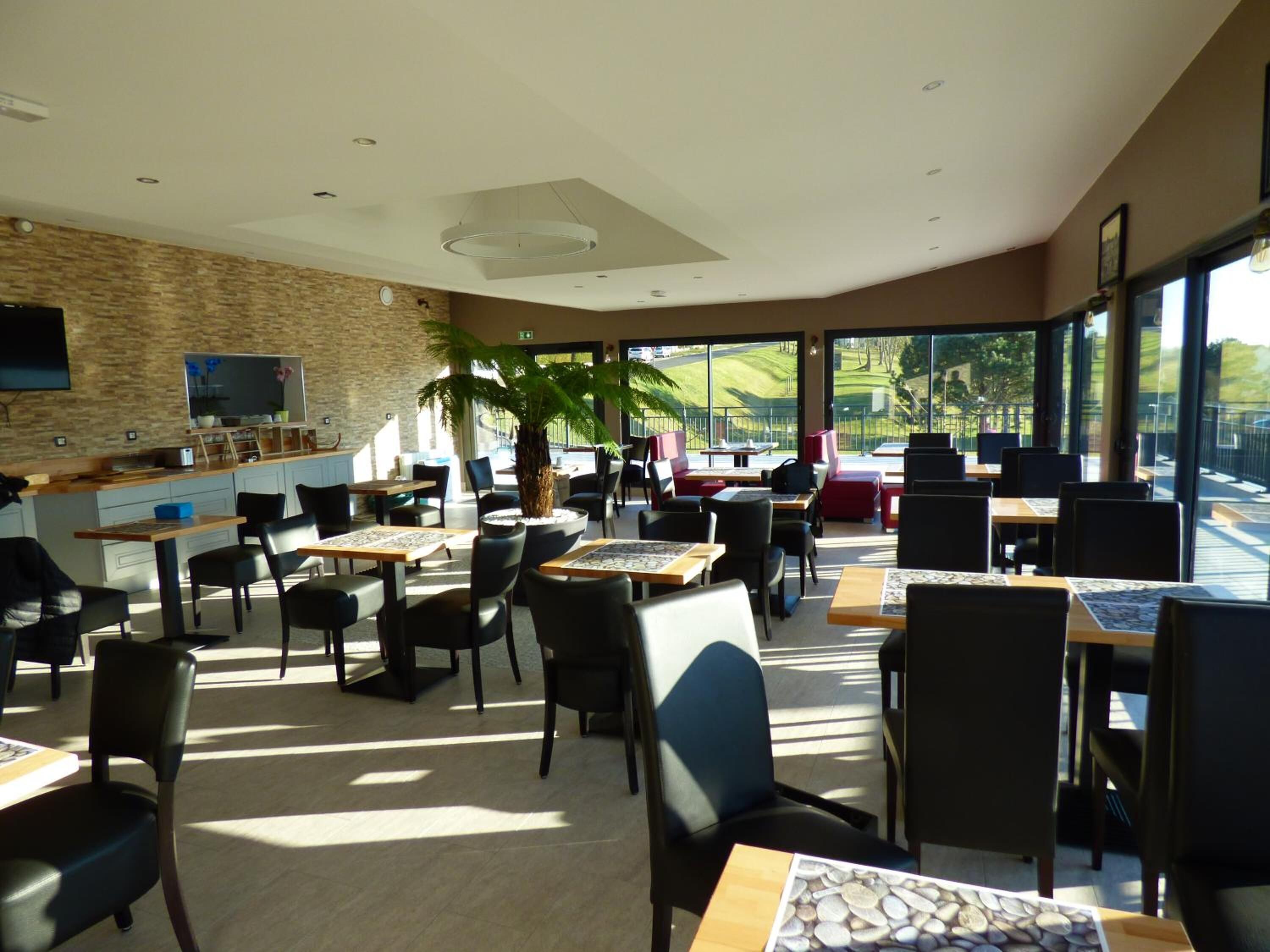 A modern restaurant with a stone wall, a flat-screen TV, and a large window offering a view of the outdoors.