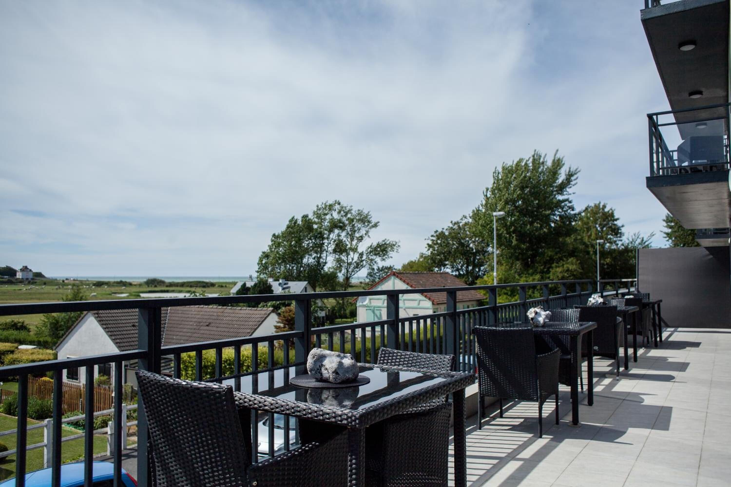 Una terraza con mesas al aire libre, vistas del paisaje y una edificación al fondo.
