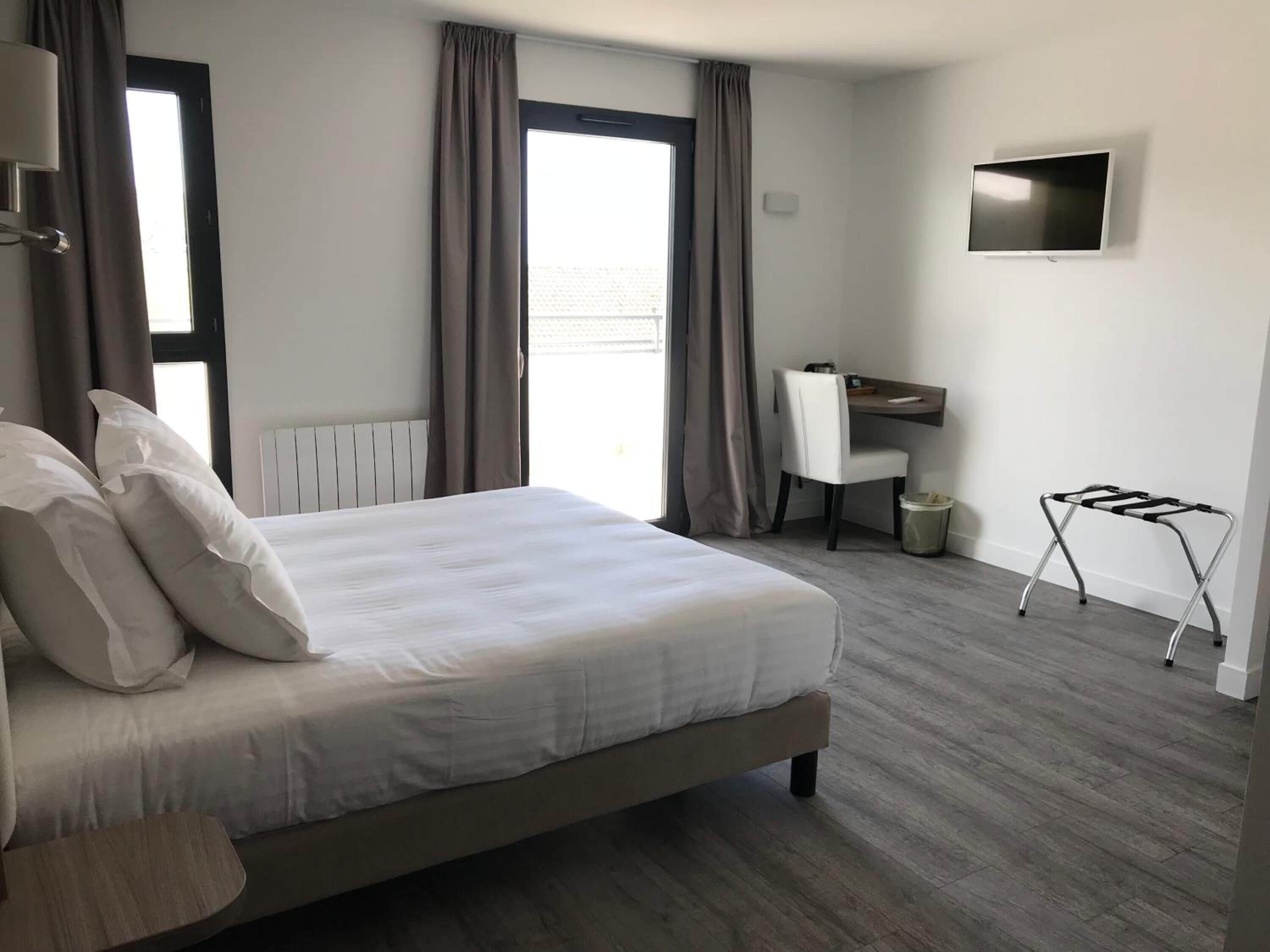 Een hotelkamer met een bed, een bureau, een stoel, een televisie en een radiator.