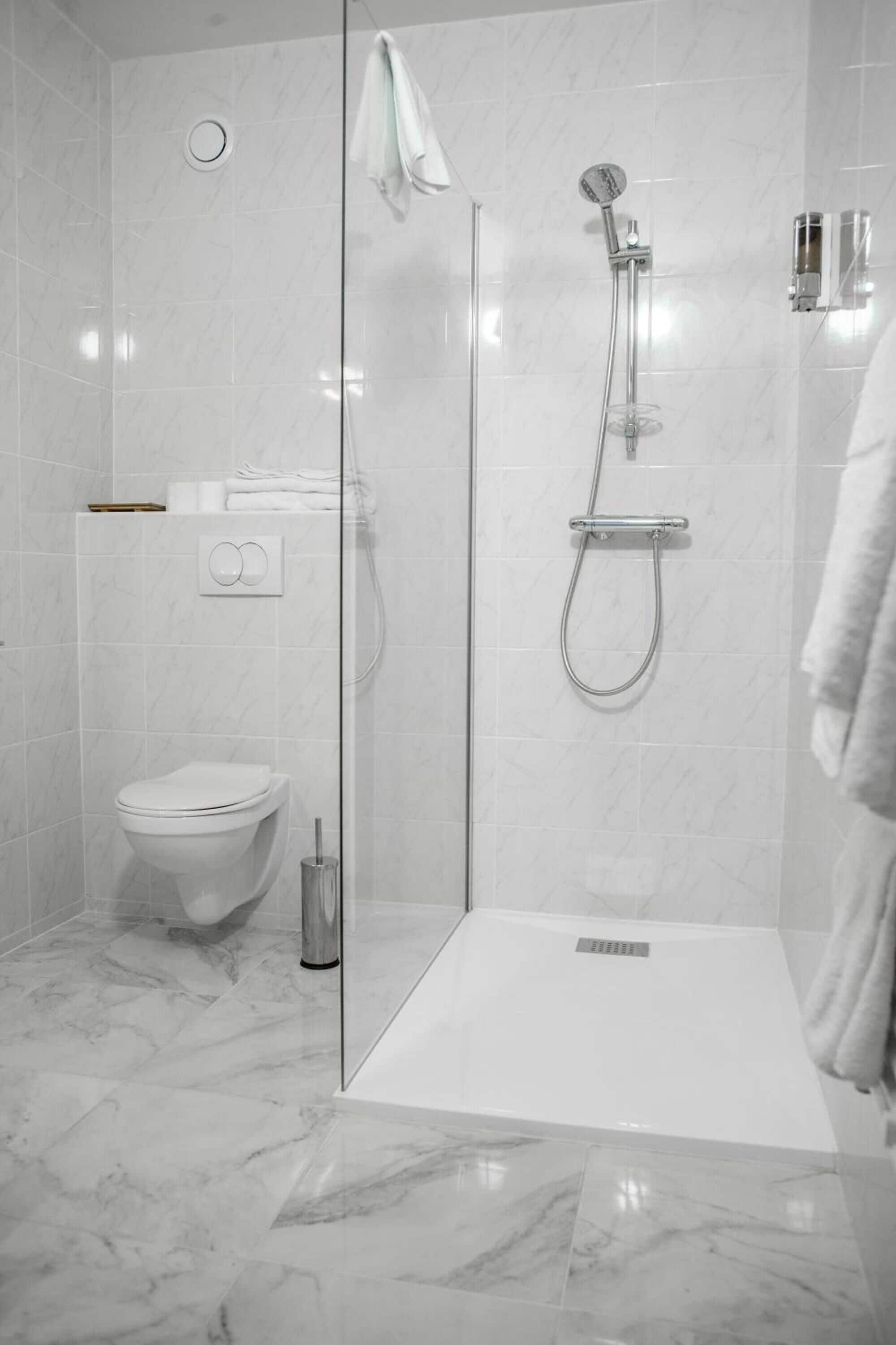 Une salle de bain moderne avec une douche à parois de verre, des toilettes et un porte-serviettes.