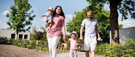 A family walking on a gravel path with trees and a building in the background.
