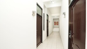 Um corredor com piso de azulejos brancos e portas de madeira escura.