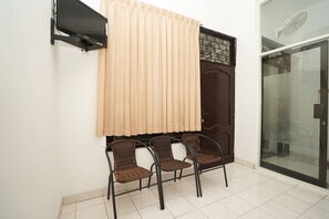 A room with a sliding glass door, a wall-mounted TV, and three wicker chairs.