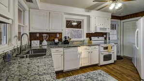 A kitchen with white cabinets, granite countertops, a dishwasher, an oven, and a ceiling fan. - Blessed Mountain Acres w/ Leather Recliners, Hot tub, Swing close to parkway (Sevierville)