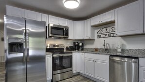 A modern kitchen with stainless steel appliances, white cabinetry, and a granite countertop. - Blessed Mountain Acres w/ Leather Recliners, Hot tub, Swing close to parkway (Sevierville)