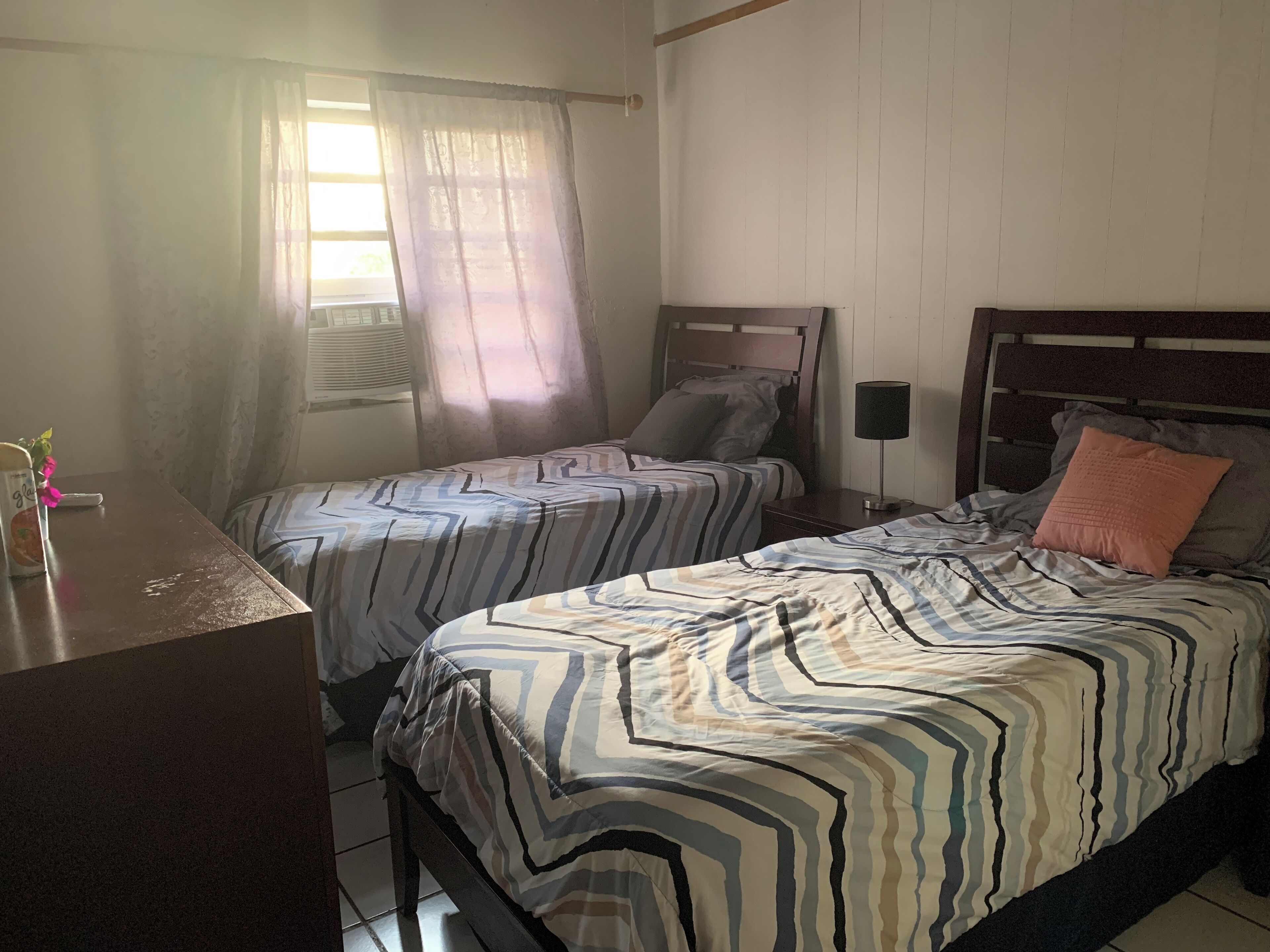 A room with two beds, a desk, and a lamp.