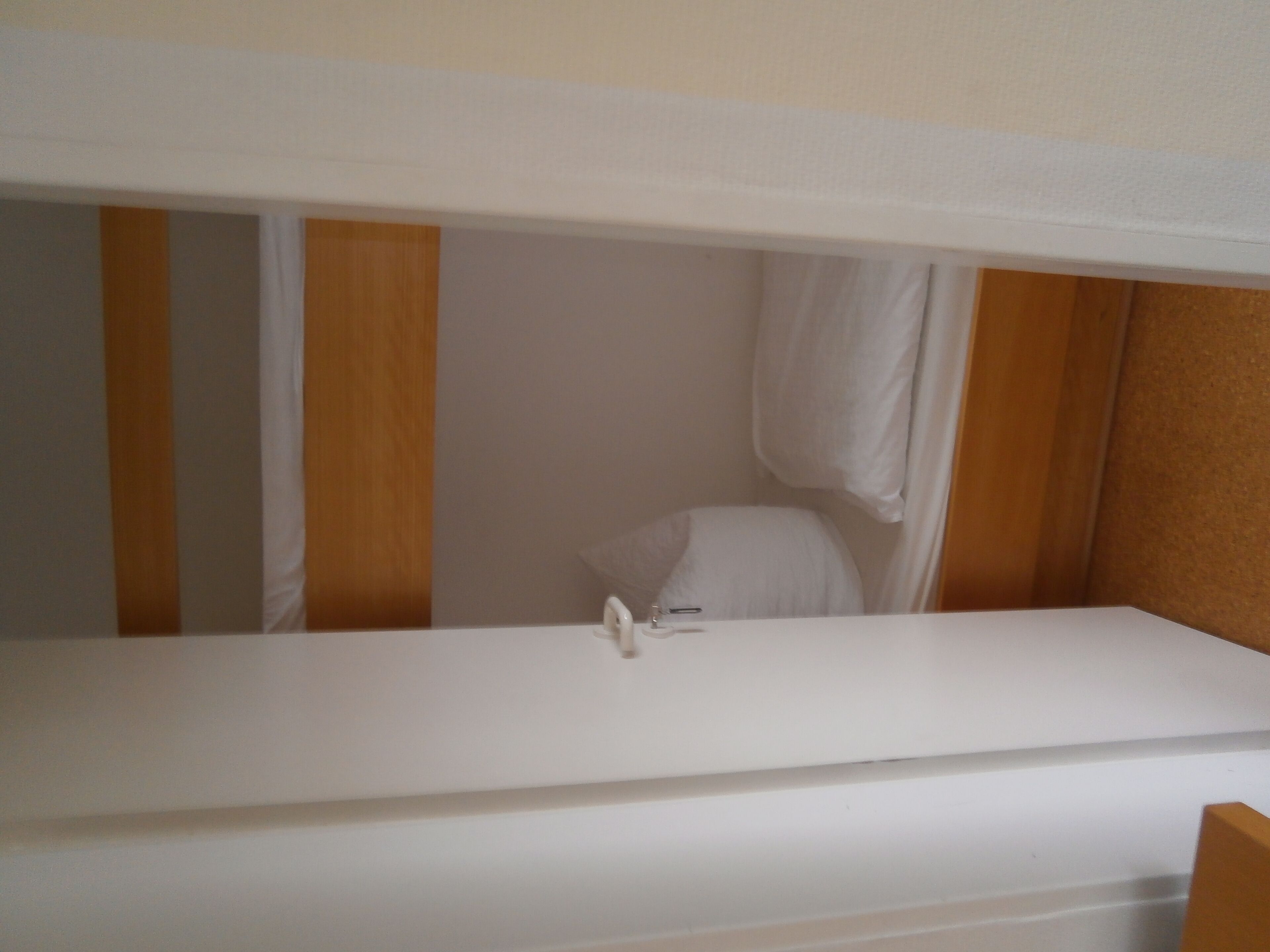 A bunk bed with a white mattress and a small bedside table.