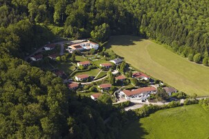 Vista aérea de uma área residencial com várias casas, cercada por floresta densa.