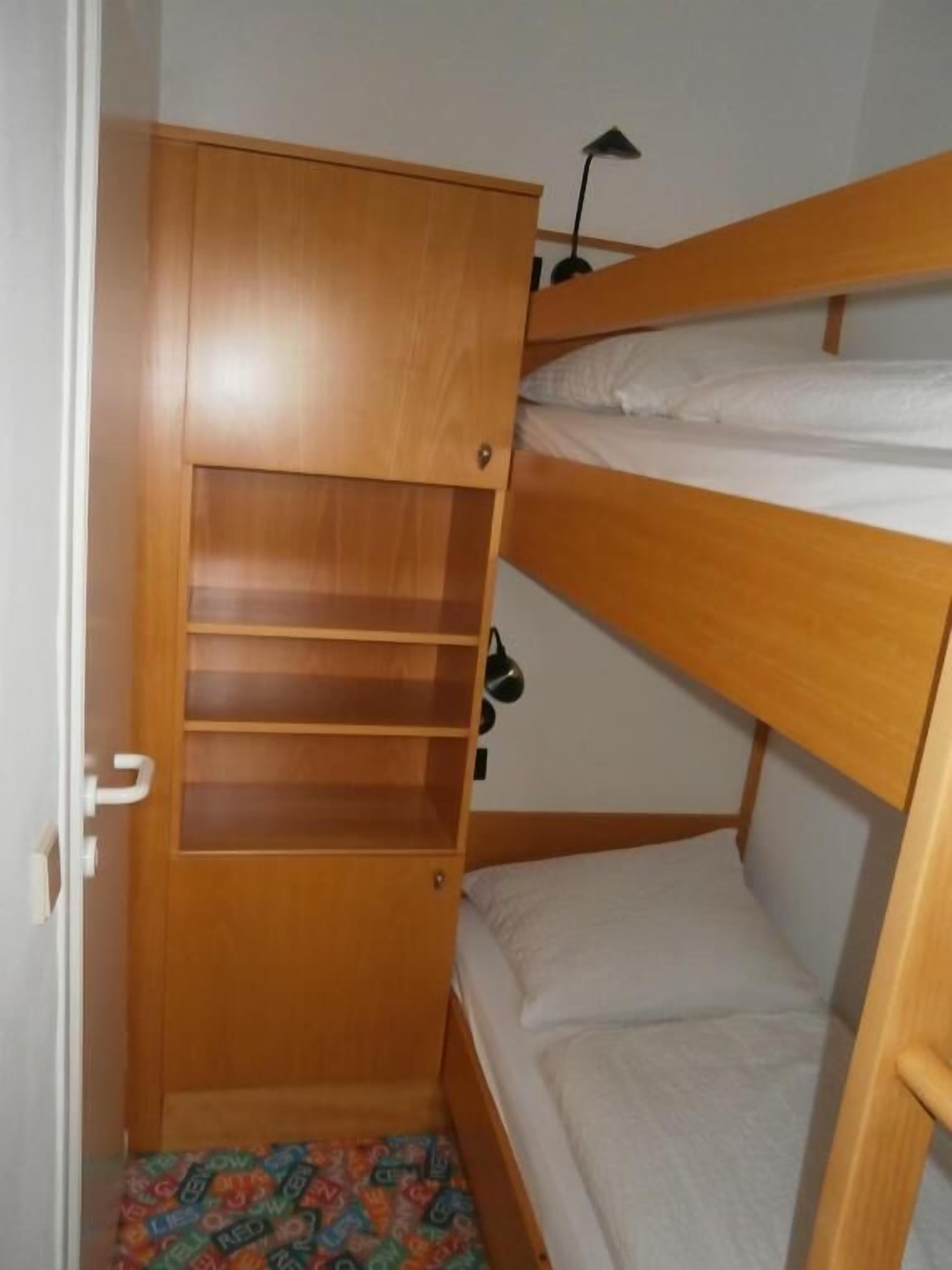 A bunk bed with a wooden wardrobe underneath.