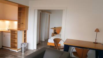 Una habitación de hotel pequeña con kitchenette, una cama, un escritorio y una silla.