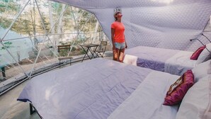 Un interior amplio y moderno con una cama grande, una zona de estar y vistas a través de una estructura de ventana geométrica.