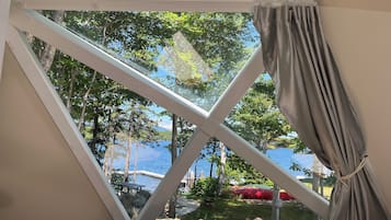 Et værelse med udsigt til en sø, et picnicbord og en rød båd.