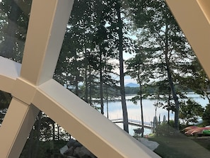 Vista a través de una ventana, con el reflejo de árboles y una montaña a lo lejos.