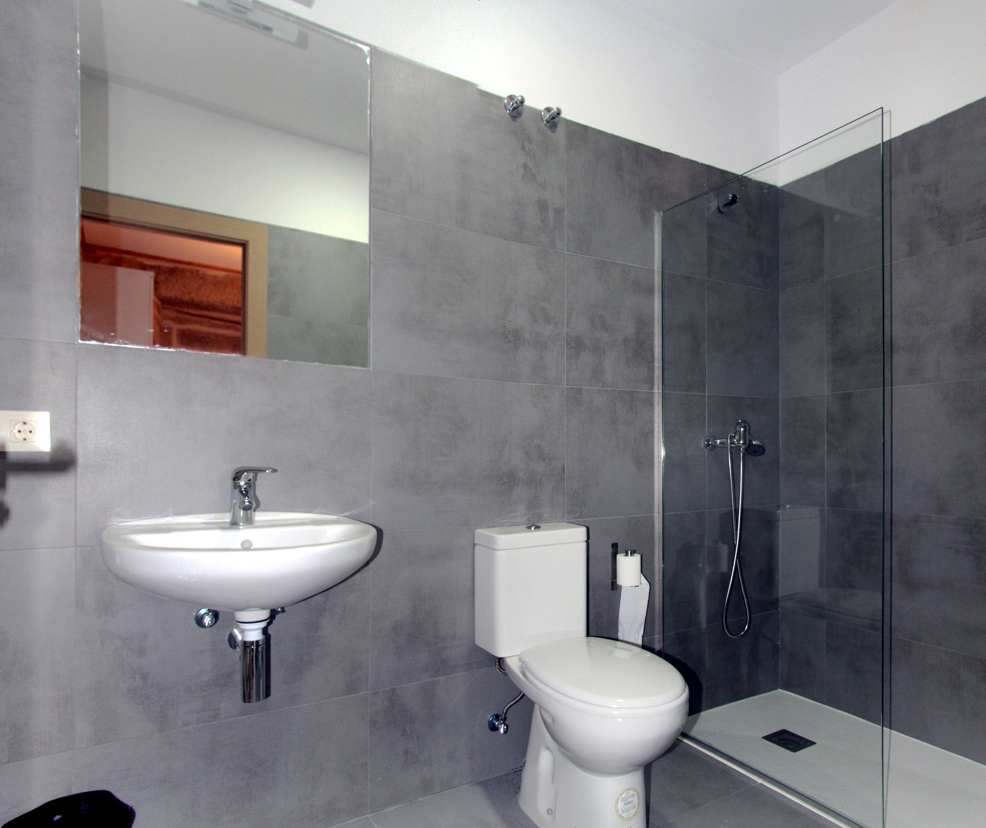 Un baño moderno con lavabo, inodoro y ducha con cerramiento de vidrio.