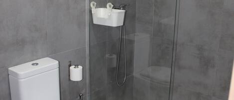 A bathroom with a toilet, a glass shower enclosure, and a white sink.