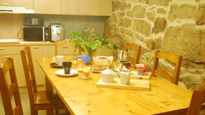 A wooden dining table with chairs, a plant, and breakfast items. - Casa do Mosteiro (Xinzo de Limia)