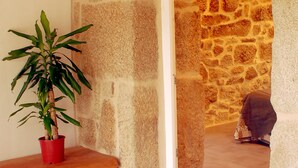 A stone wall, a wooden bench, and a potted plant in a corner. - Casa do Mosteiro (Xinzo de Limia)