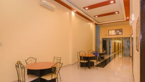 A dining area with a round table and chairs, a corridor with a glass partition, and a ceiling with recessed lighting. - Collection O Banda Aceh near Masjid Raya Baiturrahman formerly Hotel Mulana (Banda Aceh)