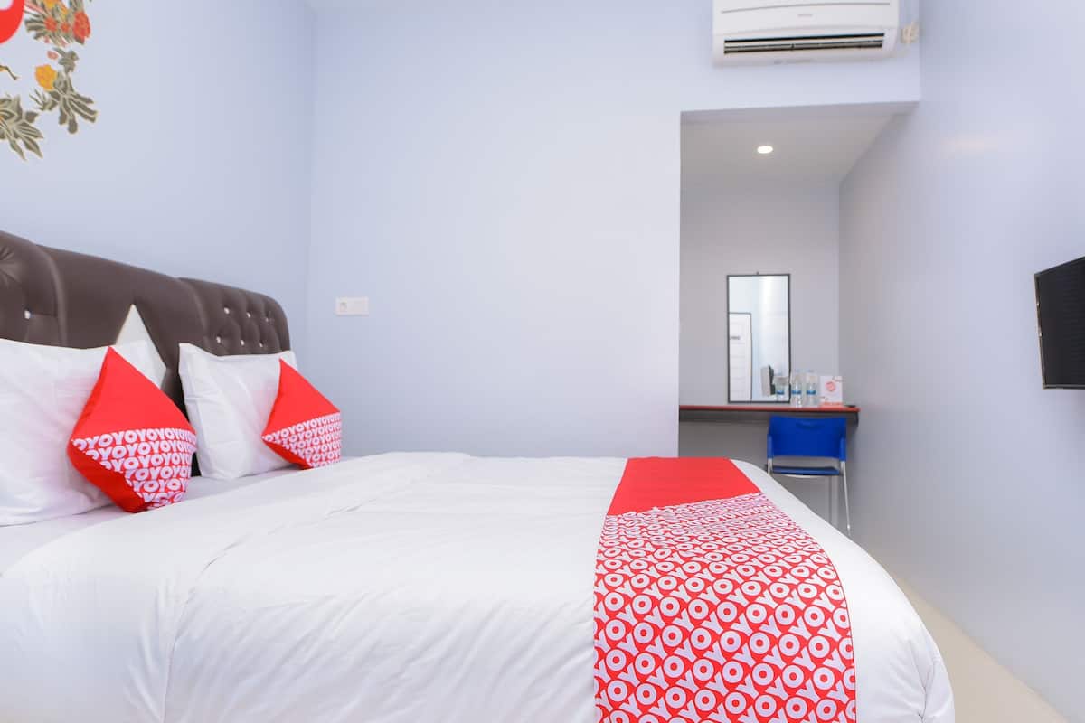 Une chambre d’hôtel avec un lit, un bureau et un miroir.