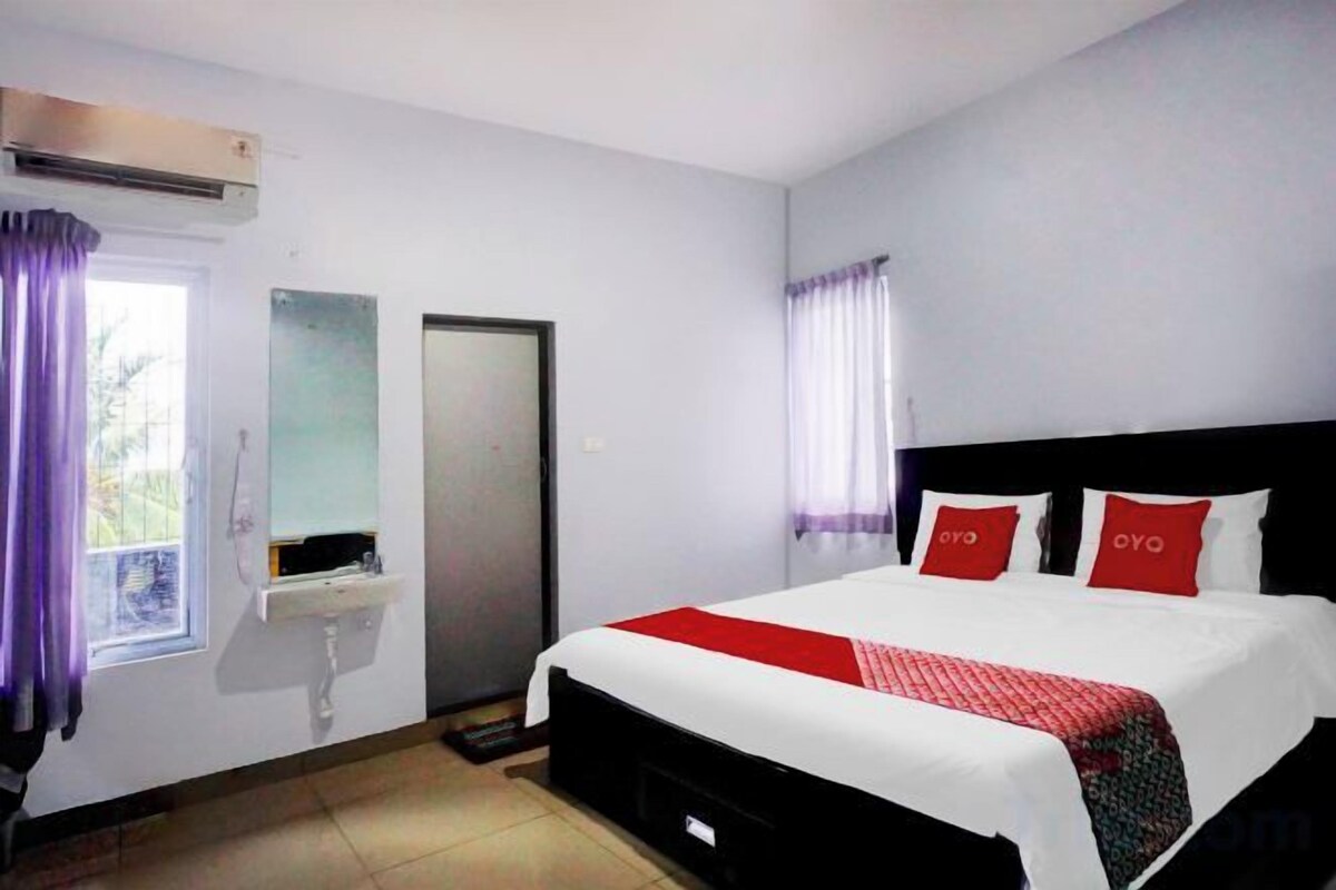 Une chambre d’hôtel avec un lit, une fenêtre avec des rideaux, un lavabo et un miroir.