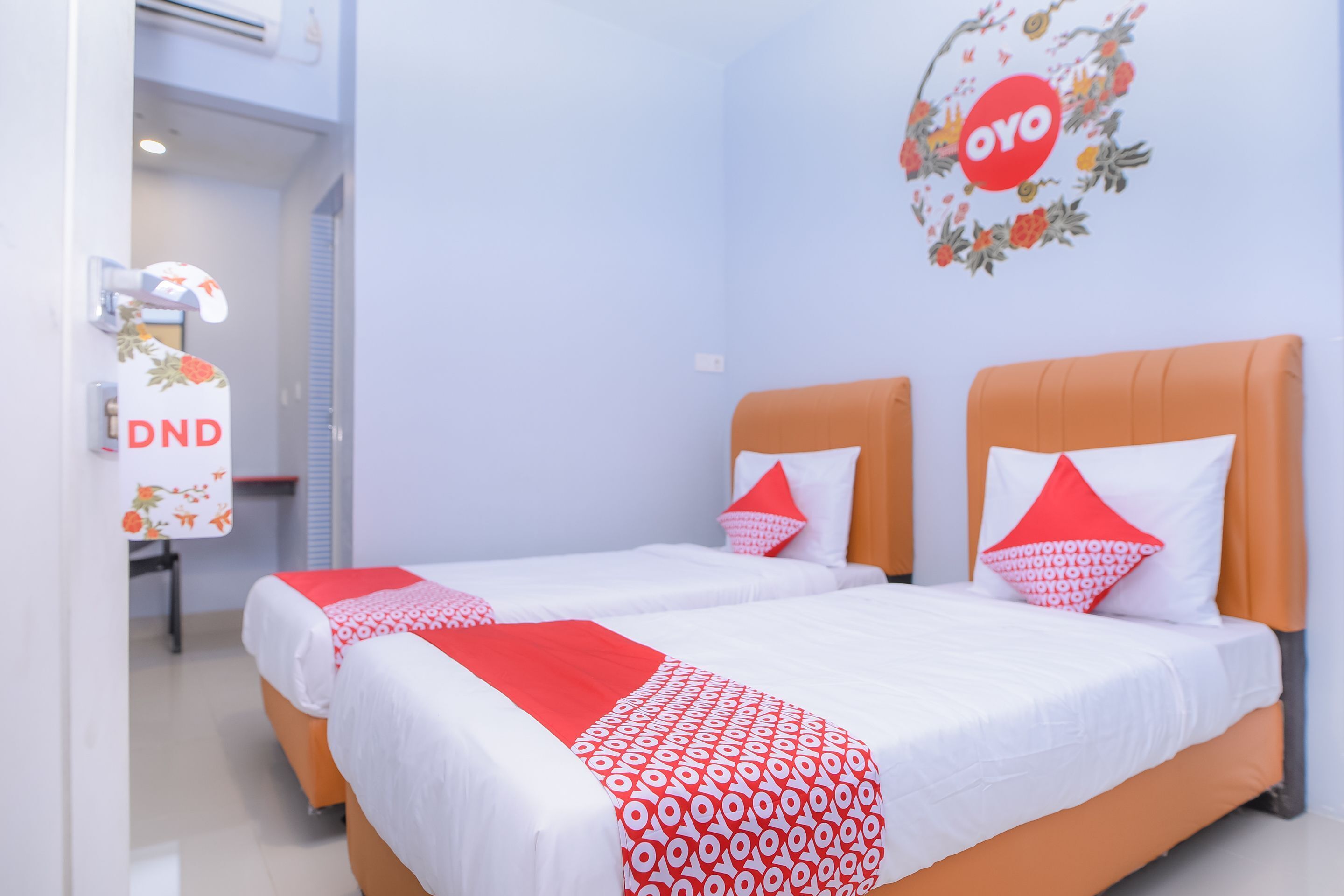Ein Hotelzimmer mit zwei Betten, einem Schreibtisch mit Stuhl und einer Wand-Klimaanlage.