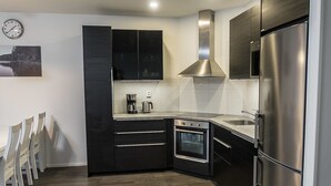 A modern kitchen with dark cabinetry, stainless steel appliances, and a built-in oven.